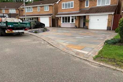 Wide-angle view of modern home with spacious driveway with Raj Green Indian Sandstone 900x600 slabs, complemented by stone edging.