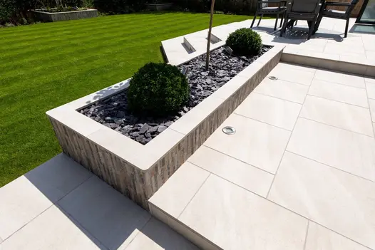 Stylish outdoor area with Allora Bianco porcelain, steps and raised planters that complement the contemporary setting.
