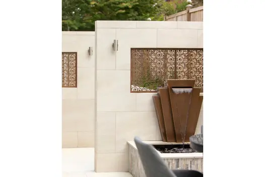 A well-lit garden featuring Allora Bianco porcelain paving, with clean lines and a light-reflective surface enhancing the outdoor space.