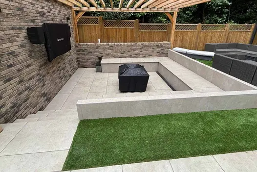Almeria Beige Porcelain Cladding used to finish a modern sunken seating area, with matching beige porcelain paving and a timber pergola overhead for a clean, contemporary outdoor space.