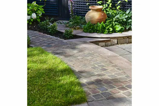Autumn Brown Sandstone Setts forming a curved garden pathway alongside a lawn and raised planting bed with feature pottery.