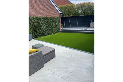 A modern back garden featuring County Light 900x600 porcelain slabs, creating a sleek and spacious outdoor setting.