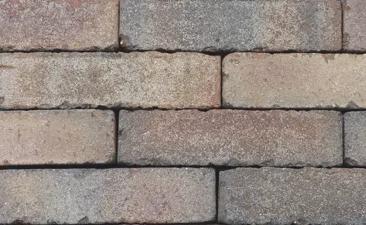 Close-up of 10 Bexhill clay pavers laid in running bond pattern, showing tones of red and grey, with tumbled edges.