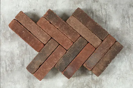 12 Antique Red brick pavers laid in a double herringbone pattern against a pale background, showing bricks’ tones of red and grey. 
