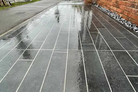 Charcoal Plank Porcelain paving laid in a linear pattern on a driveway, with contrasting grout lines and decorative gravel edging.