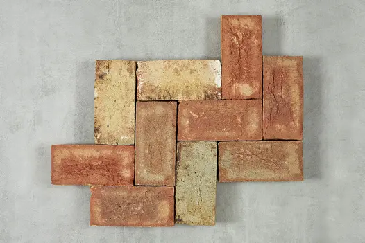 11 red and cream Cotswold clay pavers, arranged in a herringbone pattern of 3 courses of 4 bricks each against light background. 