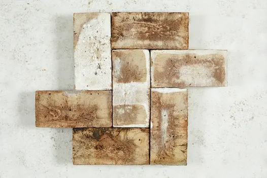 7 London Mixture Belgian bricks laid as small section of herringbone pattern against white background. Free UK delivery available.