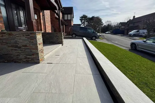 Bright and airy patio using County Light 900x600 porcelain paving slabs, ideal for open garden spaces.