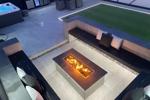 An elegant outdoor seating area with County Light 900x600 slabs surrounding a built-in fire pit for warmth.