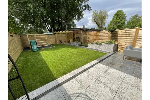 Contemporary garden with patterned Deco 600x600 porcelain paving, green lawn, and horizontal timber fencing for a modern finish.