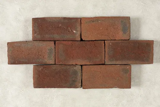 On a light background, seven Dorset antique clay pavers arranged in pattern to show colour variation and texture.