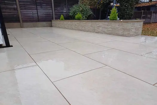 A refined garden patio laid with White Quartz 1200x600 porcelain paving and neat raised beds.