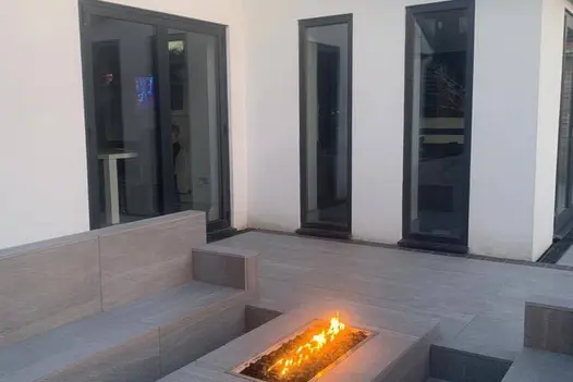 Overland Silver paving surrounding a linear fire feature, complementing the crisp white exterior.
