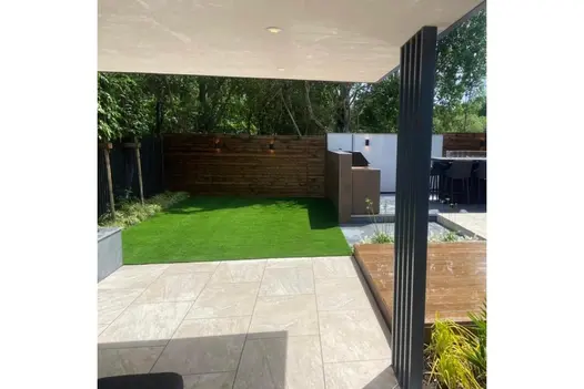 Modern garden patio using Gaja Beige Porcelain, with covered area, neat lawn and built-in barbeque area.