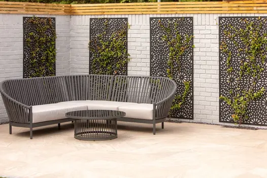 Outdoor seating area with Gaja Beige 900x600 Porcelain Paving, framed by gabion wall panels and timber fencing.