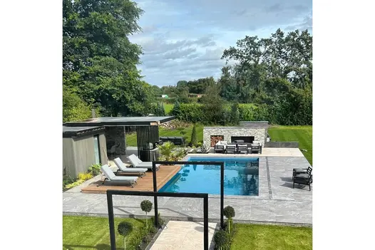 Poolside garden design featuring Gaja Grey 900x600 Porcelain Paving and a stylish outdoor seating area.