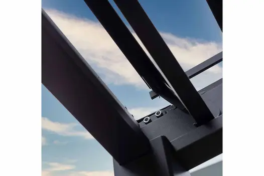 Close-up of corner of Anthracite Grey aluminium frame of Proteus Pergola, its tiltable louvres in fully open position, sky above. 