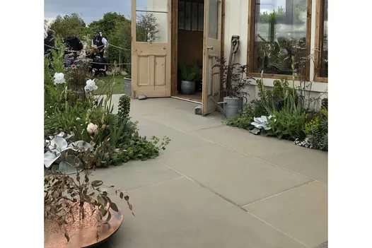 Heath Smooth Indian Sandstone paving laid outside a garden room, surrounded by cottage-style planting.
