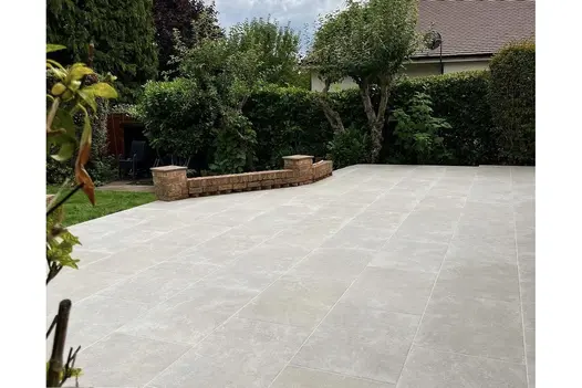 Contemporary patio using Heritage Chalk 900x600 Porcelain Slabs with a soft neutral finish and modern brick edging.