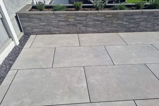 Raised garden with Heritage Grey 900x600 Porcelain Paving, blending with slate chippings and low walls.