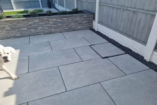 Neat patio layout using Heritage Grey 900x600 Porcelain Paving, set against a raised grey sleeper bed.