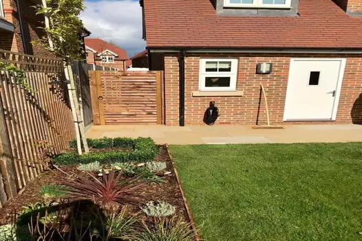A well-landscaped garden featuring a pathway of Mint Smooth Sandstone slabs leading to a wooden gate.