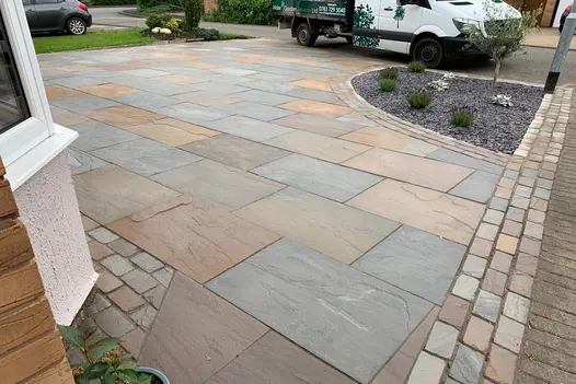 Driveway featuring Raj Green Indian Sandstone 900x600 slabs with mixed stone setts and gravel border with plants.