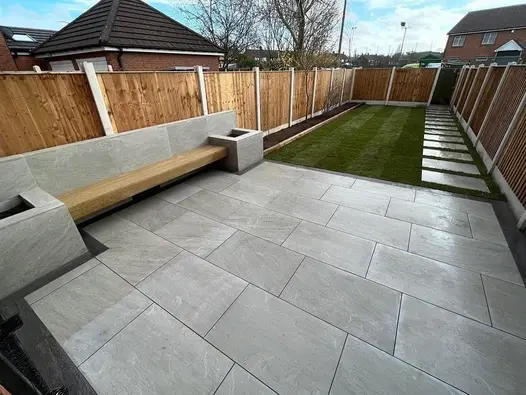 Contemporary garden with Kandla Grey Porcelain Paving, built-in bench seating and stepping stones across the lawn.