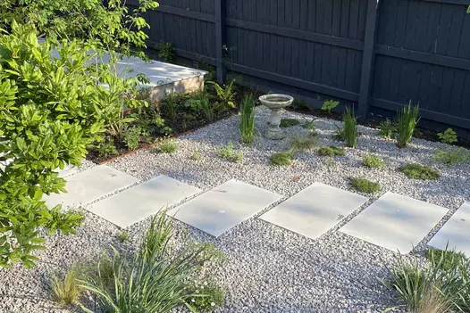 Dove Grey Smooth Indian Sandstone stepping stones set within a gravel garden, surrounded by planting and a small birdbath.