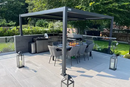 Outdoor dining area with Overland Silver 1200x600 Porcelain Paving, shaded by a sleek pergola.