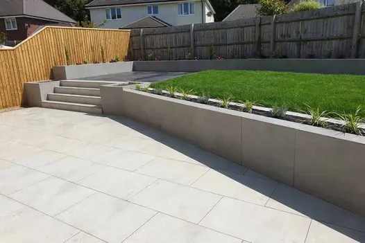 Matte Grey Porcelain Cladding used to face a modern tiered retaining wall, creating clean lines between the upper lawn and lower patio terrace.