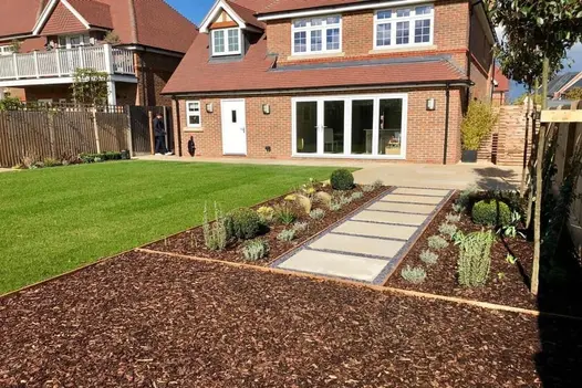 A large, open patio with Mint Smooth Sandstone paving and a decorative pathway through the lawn.