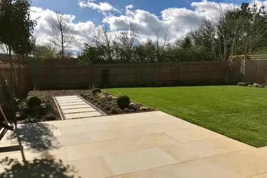 A modern outdoor space with a pathway bordered by gravel and planting, paved with Mint Smooth Sandstone.