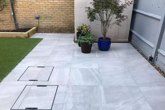 A contemporary garden with Allora Silver Porcelain paving showing marble effect, artificial lawn and built-in planters.