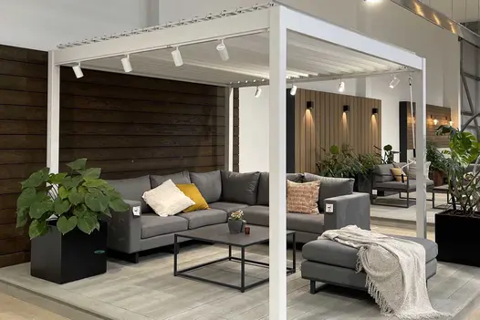 Proteus White Aluminium pergola in London Stone showroom on composite deck with furniture beneath and 8 spotlights clipped to roof.