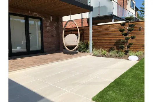 Outdoor space with hanging chair and Overland Sand Porcelain Paving, blending into the modern garden design.