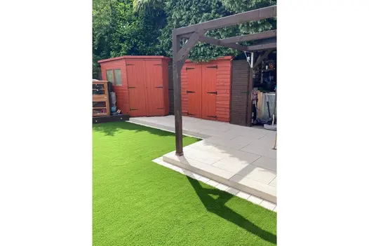 Playful garden design with a swing over artificial grass and Overland Sand paving creating a seamless walkway.
