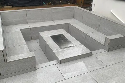 Sunken seating area finished with Overland Silver Porcelain, featuring a built-in firepit for evening use.