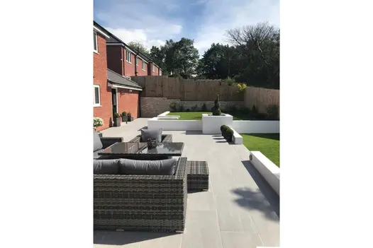 Minimalist garden lounge design featuring Overland Silver paving and clean, raised planters.