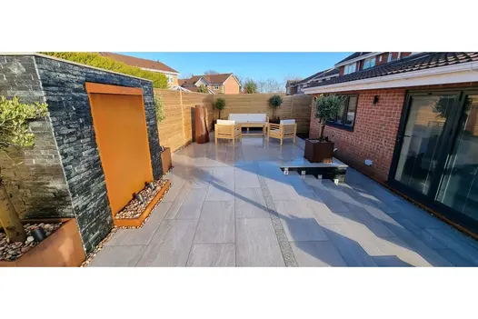 Long entrance walkway finished in Overland Silver Porcelain, complemented by timber cladding and slate walls.