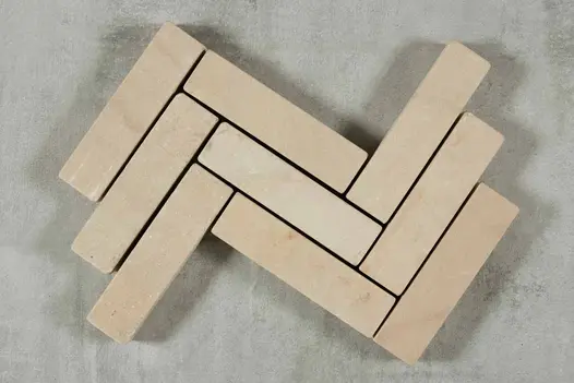 9 Harvest sandstone tumbled patio bricks placed in 3 rows, zigzag pattern, against grey background. Free UK delivery available.