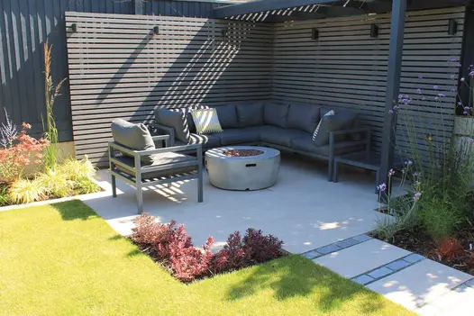 Pebble Grey Composite Fence Battens forming a modern slatted privacy wall around a contemporary garden seating area, creating clean lines and subtle contrast against the planting.