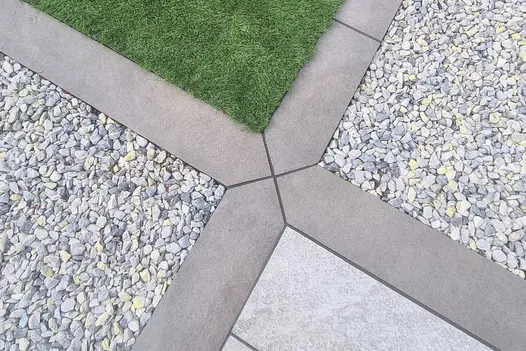 Steel Grey Porcelain Planks used as crisp edging between sections of decorative gravel and artificial lawn, creating a clean, modern geometric garden layout.