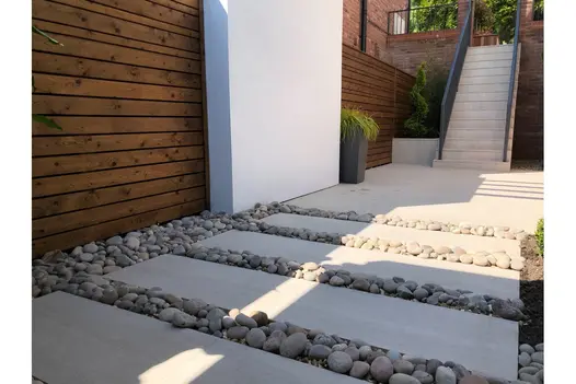 Garden steps laid in Overland Sand 900x450 Porcelain Paving, integrated with gravel and retaining walls for a tiered effect.