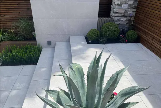 Stylish outdoor garden patio using pumice porcelain paving with minimalist planting.