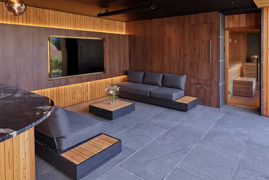 Black Sandblasted Granite paving used in a contemporary outdoor living room with timber cladding, modern seating, and an adjoining sauna.