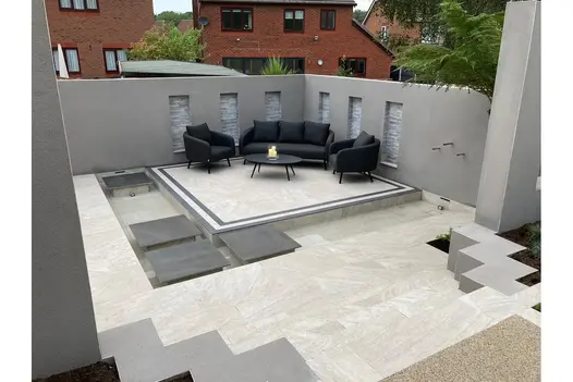 Contemporary sunken seating area with Gaja Beige Porcelain, geometric paving layout and rendered walls.