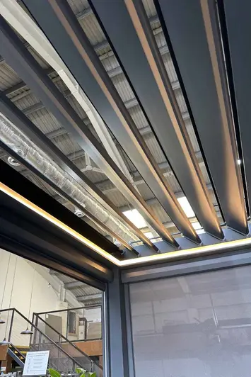 Side view of the Deluxe Anthracite Grey Metal Pergola with one side blind down and the LED lights on display.