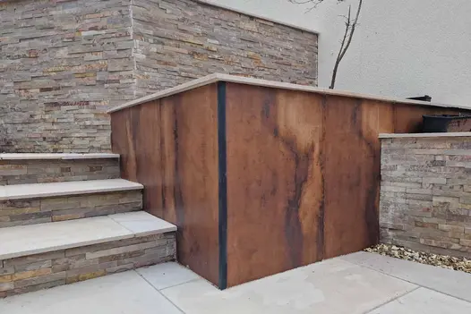 Siena Copper Porcelain Cladding installed on a raised garden wall, showcasing rich copper tones and a contemporary metallic finish alongside steps and retaining walls.