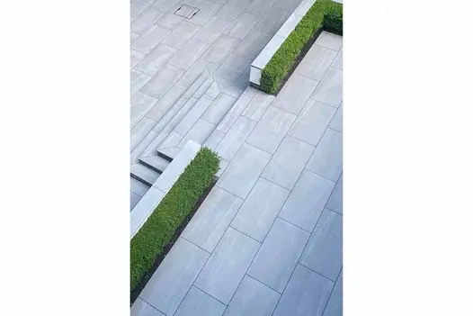 Elegant outdoor space paved with Silver 1200x600 porcelain, showcasing clean lines and modern planting.